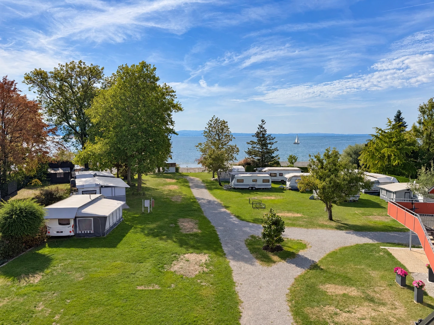 Blick von oben über den Campingplatz mit Wohnwagen, Kiesweg und dem Bodensee
